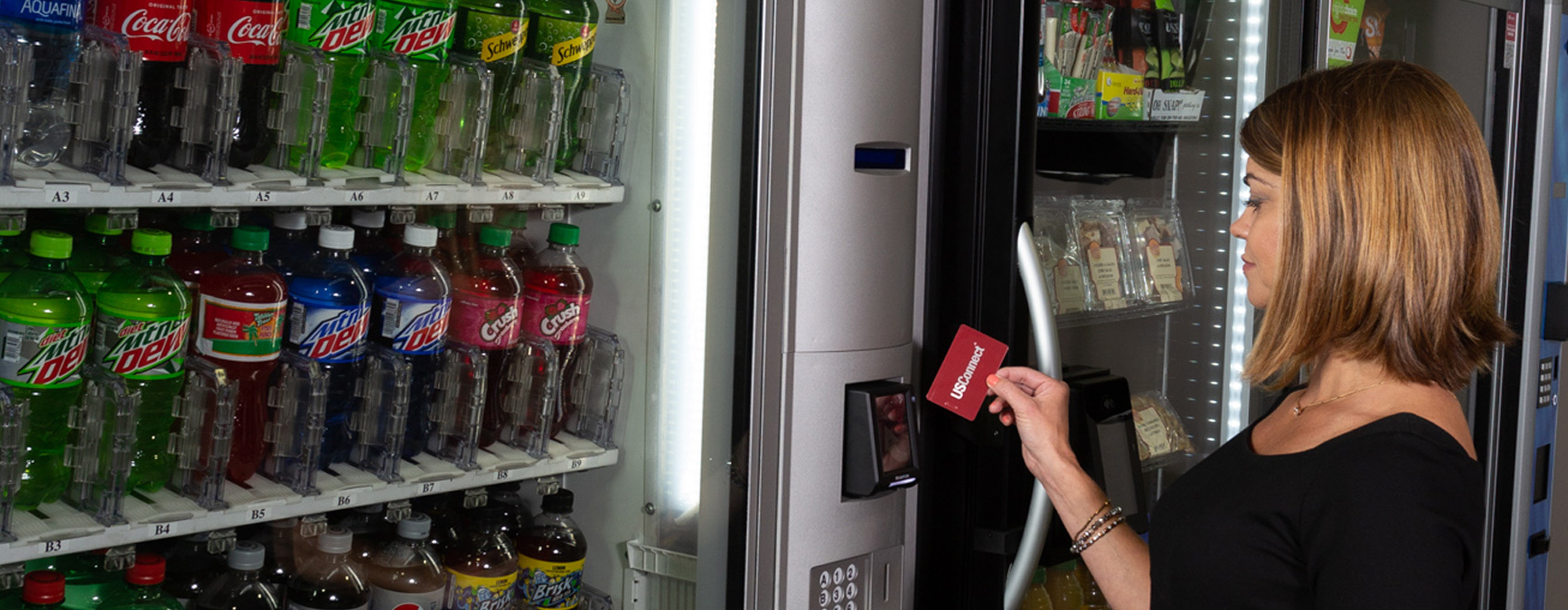 A woman beside a vending machine holding her phone